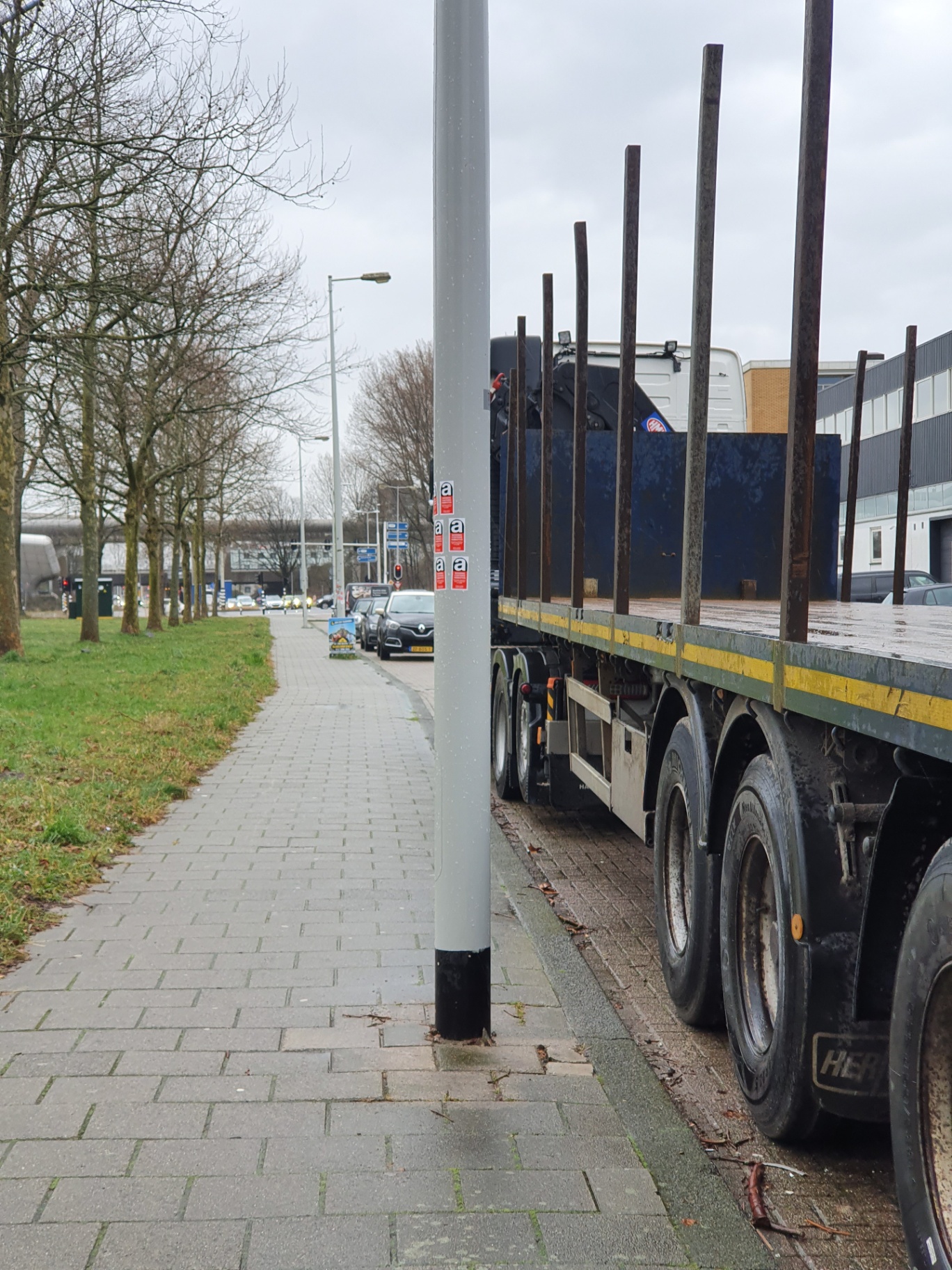 Street lamp column with red asbestos warning labels applied during the asbestos management process.