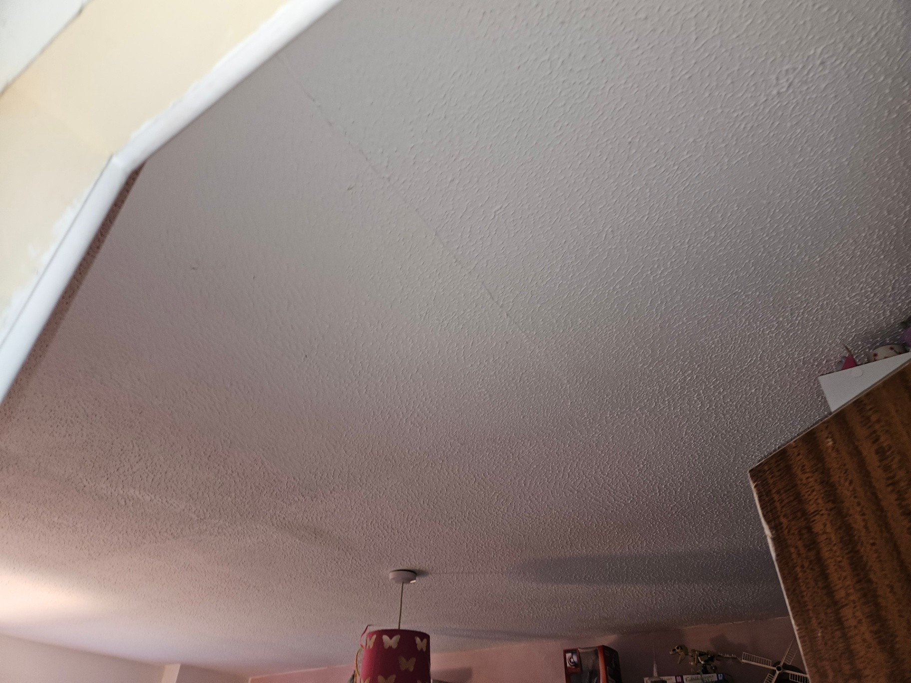 Large stippled Artex-style textured ceiling in a domestic bedroom with pendant light fitting.