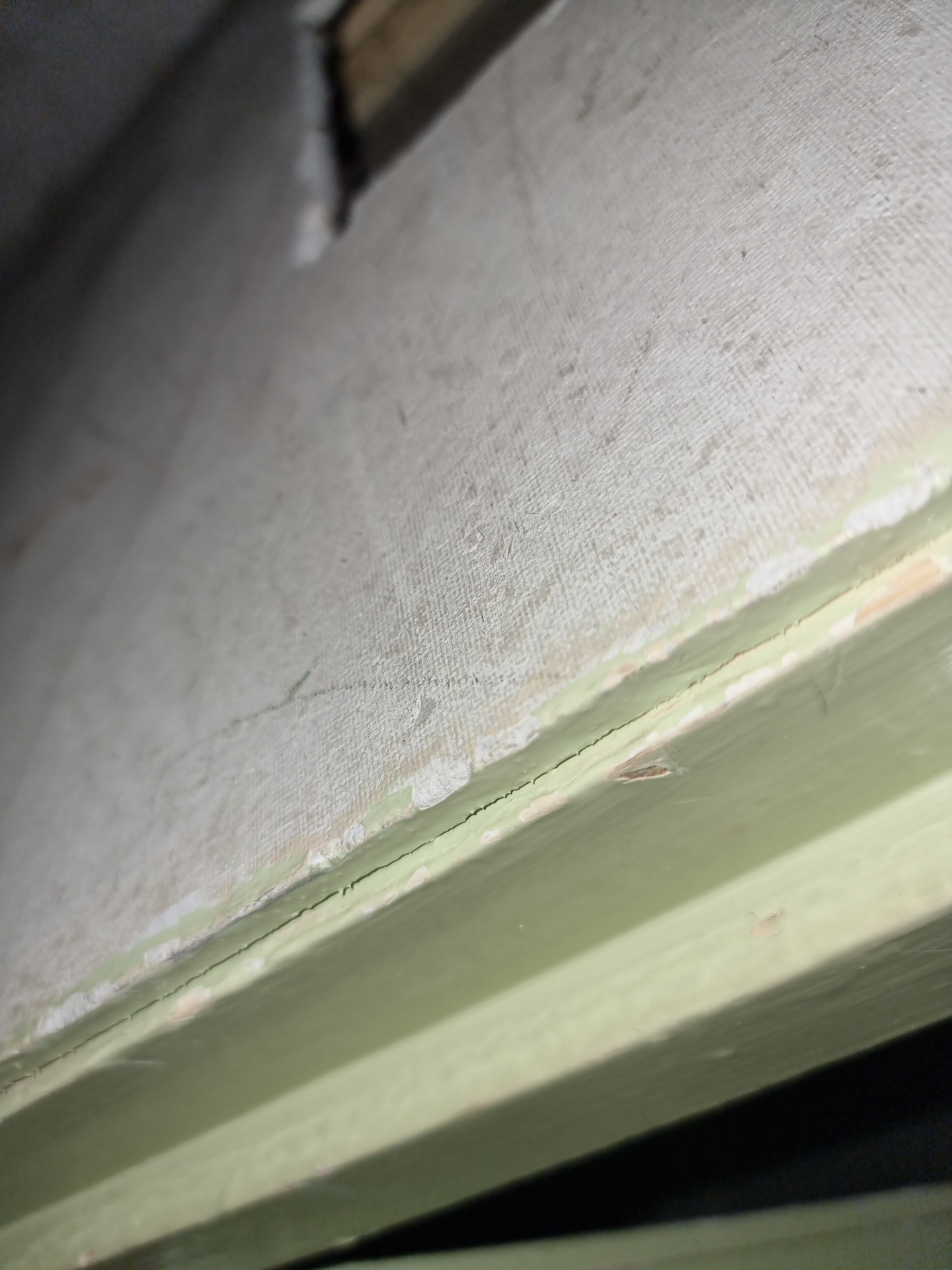 Close-up of an asbestos insulating board edge showing fibrous matrix next to painted timber trim.