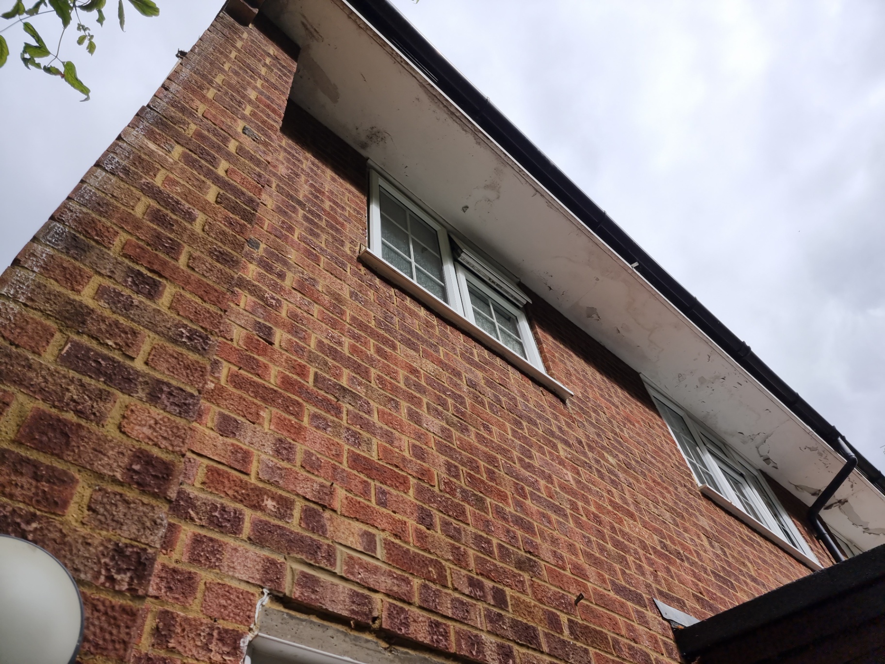 Painted soffit boards beneath roof eaves on a brick domestic property viewed from ground level.