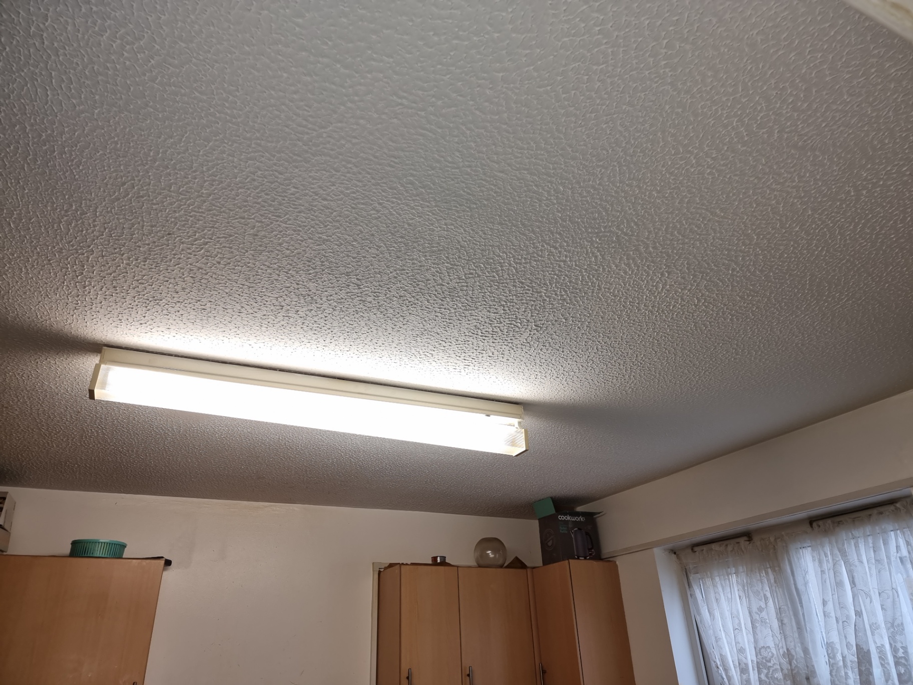 Textured coating ceiling above a fluorescent light fitting in a domestic kitchen.